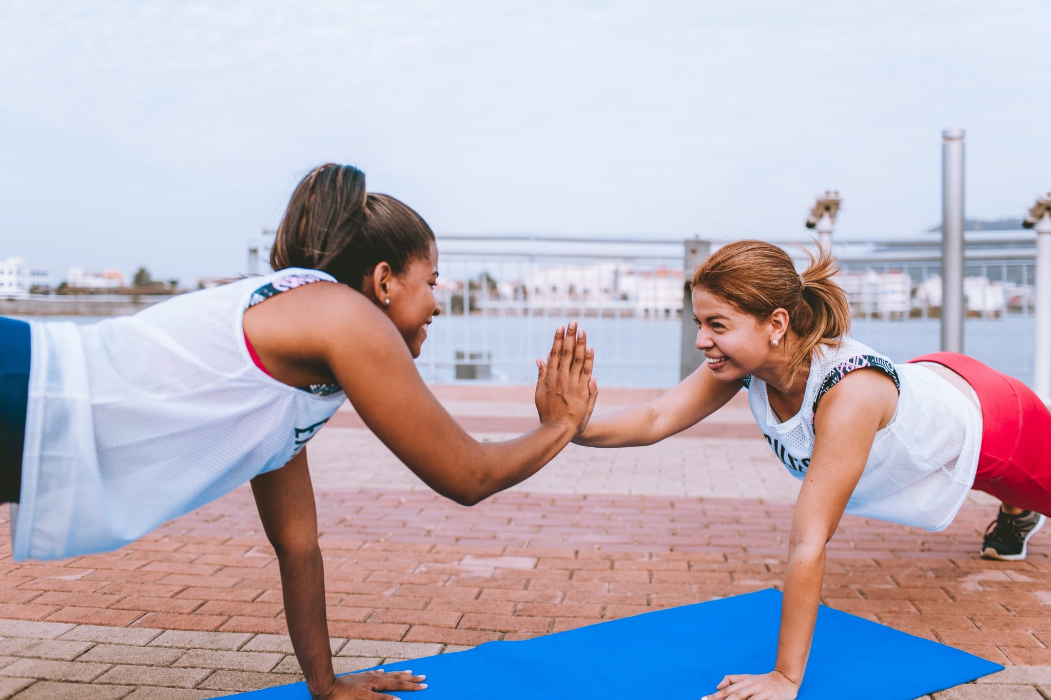 women on yoga mats high five