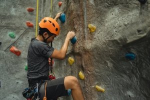  man climbing fake rock wall in orange helmet