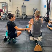 personal trainer helping a client at the rower machine
