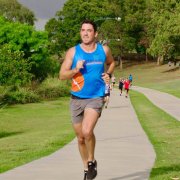 man in blue singlet running along green park