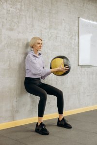 woman leaning against the wall with a fit ball 