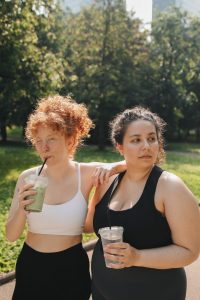 two women in workout gear sipping smoothies