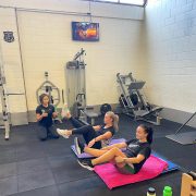 two women doing core exercises with a personal trainer