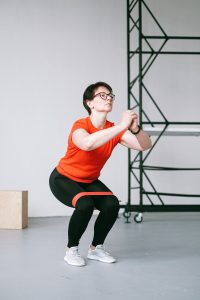 woman doing squats with a red resistance band