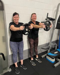 two women holding heavy weights in front of them for the studio challenge