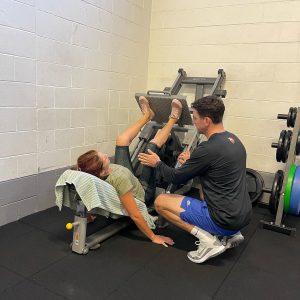 personal trainer helping woman on leg press machine