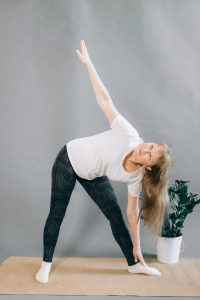 older woman in white shirt and black leggings doing yoga