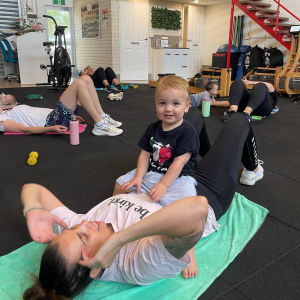 mother working out ina  gyn with her baby on her chest. It is smiling.