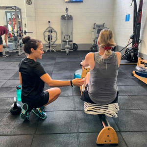 personal trainer supervising a woman on a rowing machine