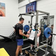 personal trainer supervising person on the bench press pushing a barbell