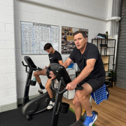 Two people exercising on stationary bikes in a gym.