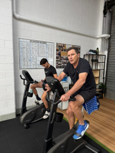 Two people exercising on stationary bikes in a gym.