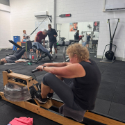 older woman using rowing machine in personal training gym