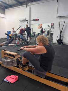 older woman using rowing machine in personal training gym