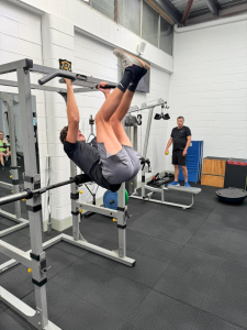 man doing feet to bar pull up