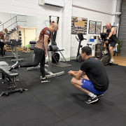 personal trainer crouched next to woman lunging with hand weights